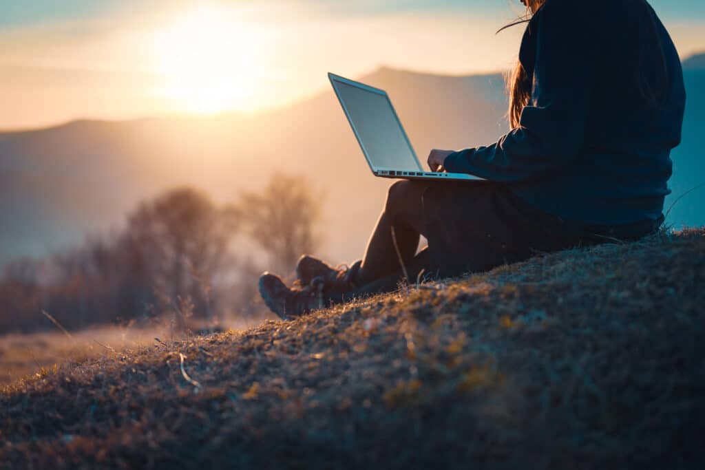 An outdoor business owner using a laptop in nature and checking on website seo, traffic, and online store revenue.