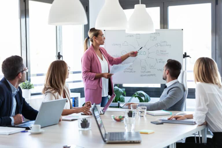 A woman presents a graph showing the various parts of SEO during a business meeting.