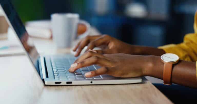 A pair of hands typing on a laptop.