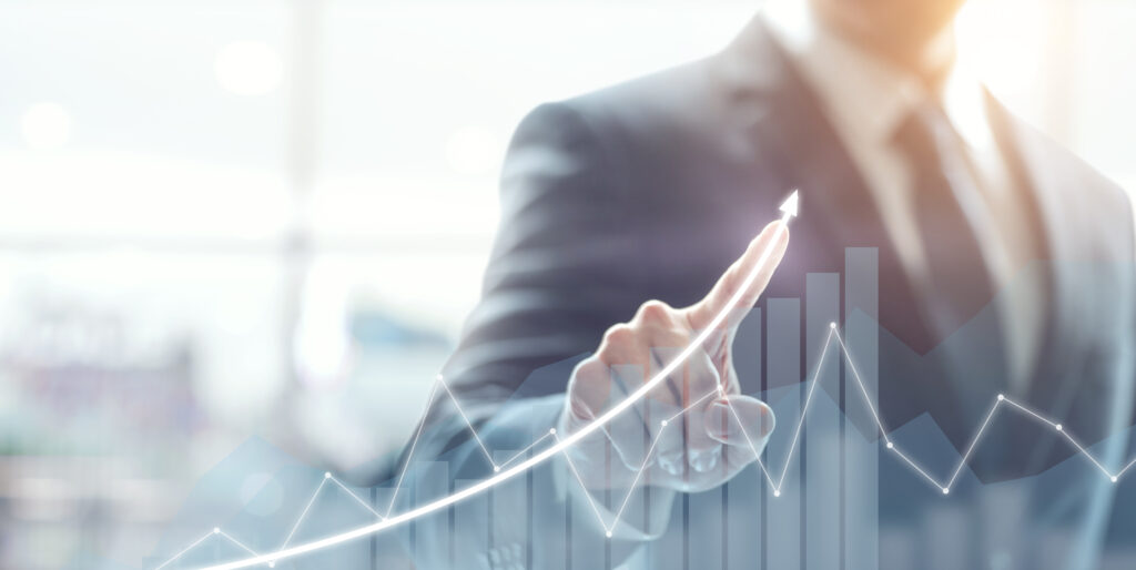 a businessman points to a bar graph going up.