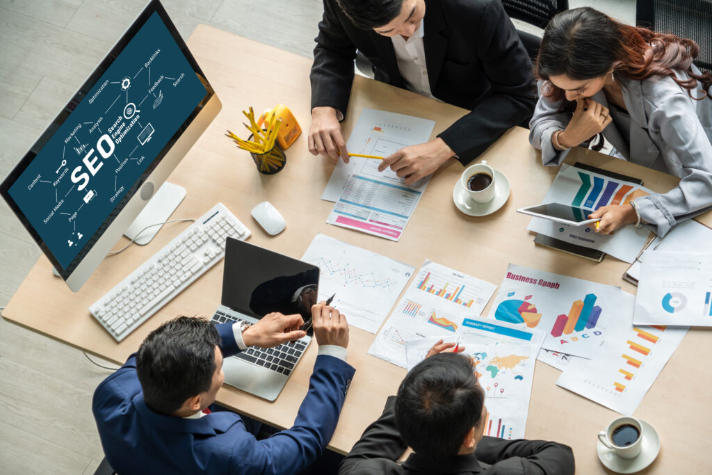 Several business people work on SEO while sitting at a desk.